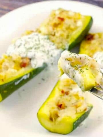 two pierogi zucchini boats on a white plate with a piece of zucchini boat on a fork