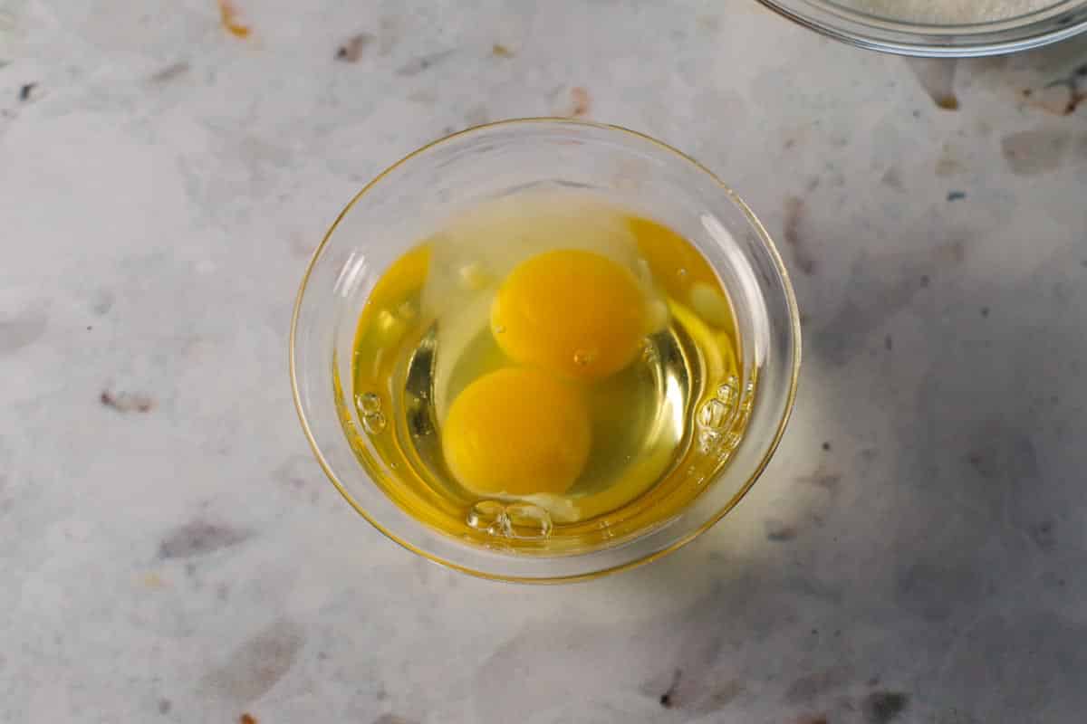 2 eggs in a glass bowl, on a counter