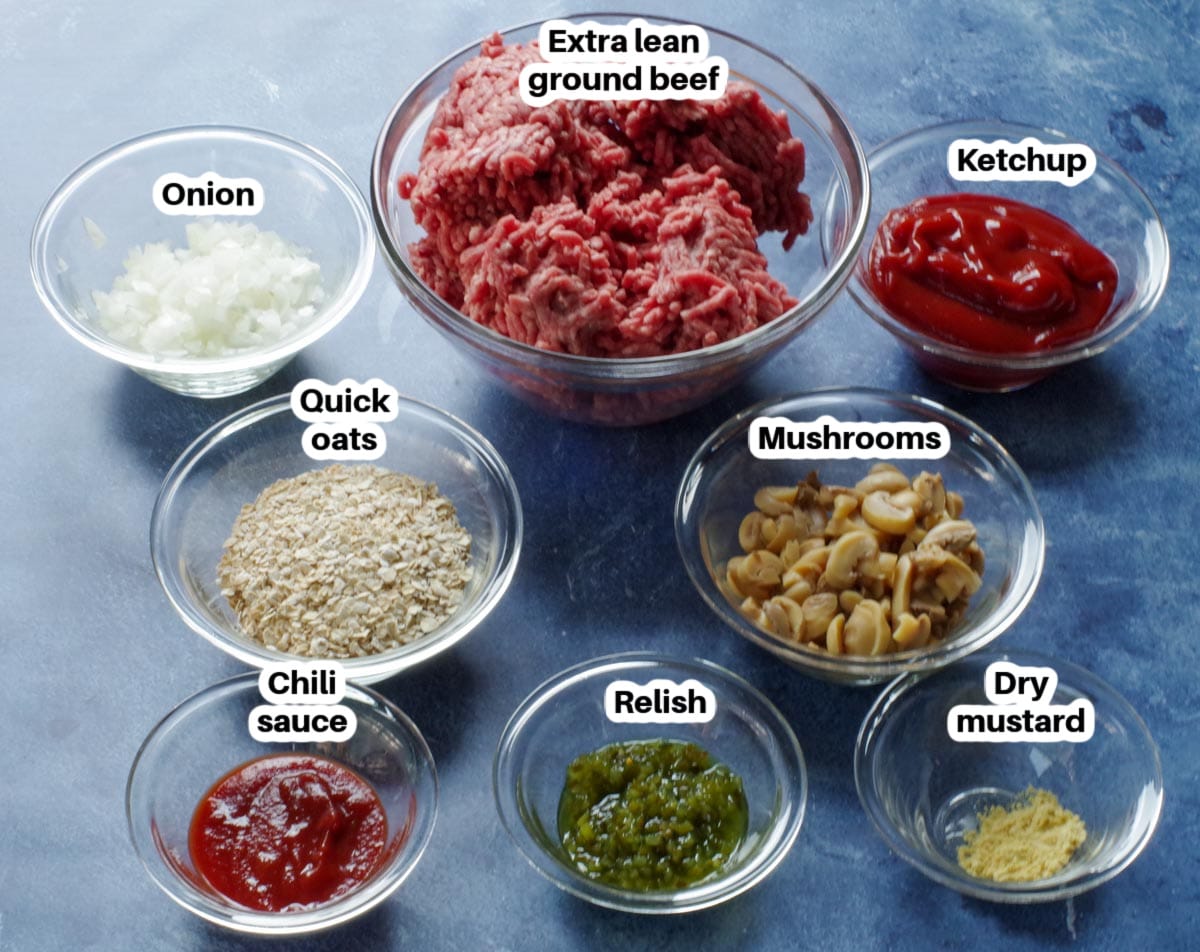 Old fashioned meatloaf ingredients in glass bowls, labelled, on blue surface