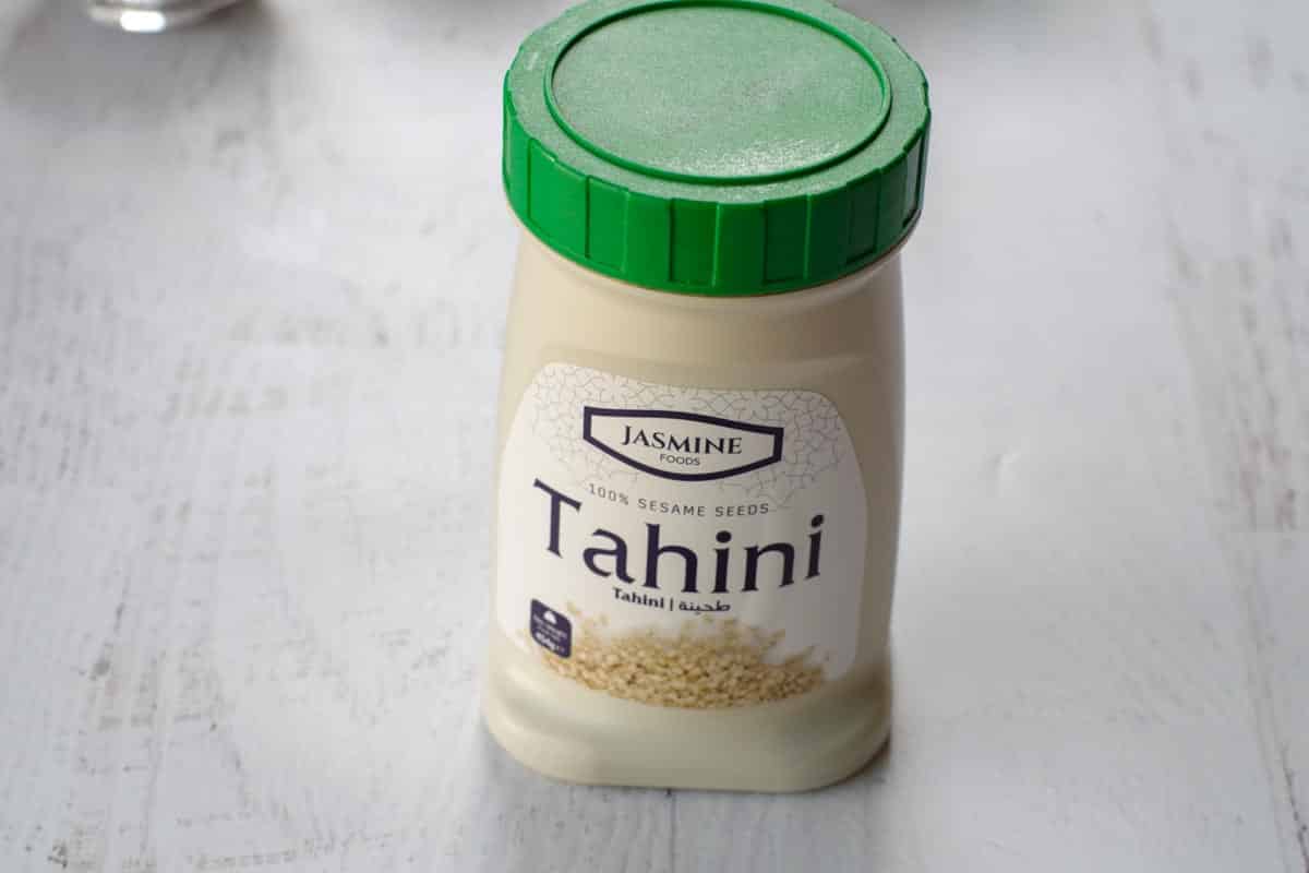 a jar of tahini (sesame see paste) on a white surface