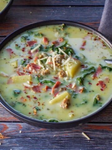slow cooker zuppa toscana ina black bowl with a spoon