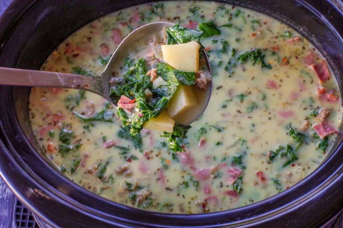 slow cooker zuppa toscana in a slow cooker with a ladle holding up soup