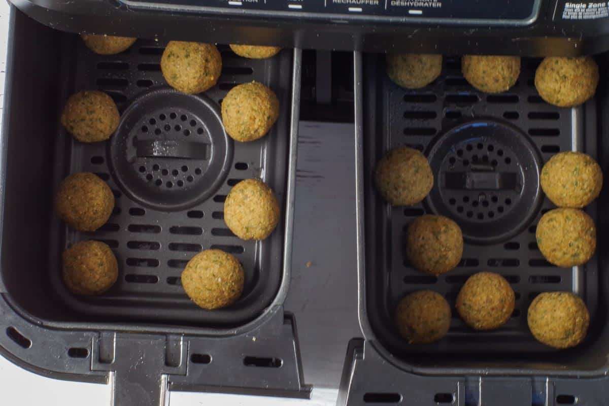 Falafel balls placed in air fryer baskets in single layer