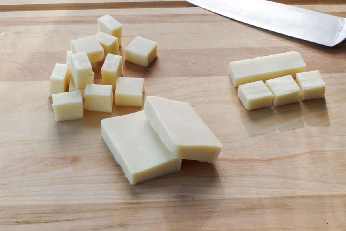 mozzarella cut into squares on wooden cutting board