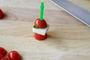 remainder of tomato added to skewer, on wooden cutting board