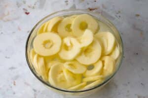 apples cut in circles in a glass bowl with lemon water
