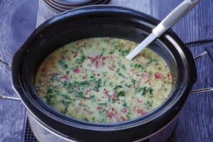 Slow cooker zuppa toscana garnished with turkey bacon and crushed red pepper