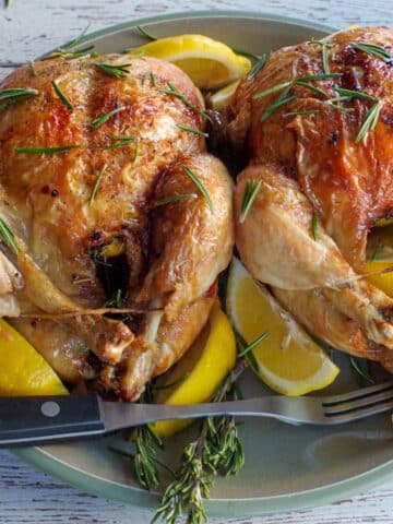 2 air fryer roast chickens on a green plate with lemon wedges