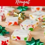 Nougat candy, cut into squares, on a wooden cutting board with green and gold mini bows
