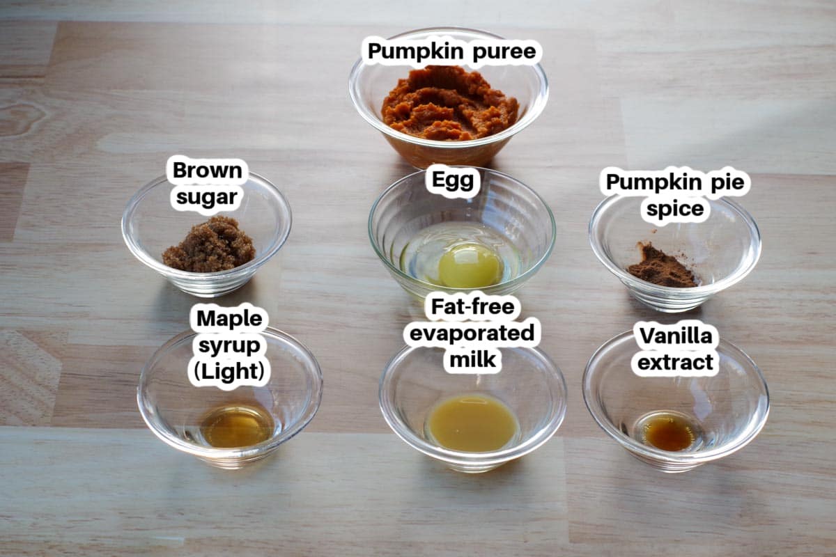 Ingredients in crustless pumpkin pie in a cup labelled, in glass bowls