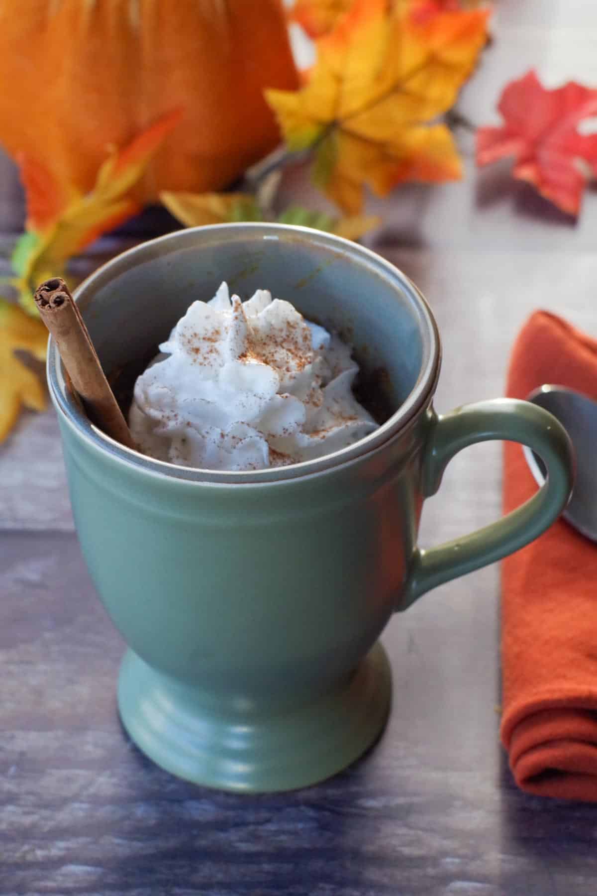 crustless pumpkin pie in a mug with whipped cream and a cinnamon stick