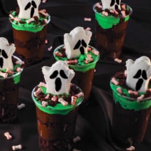 6 Boo! Halloween Dessert Cups on black surface with candy bloody bones strewn around