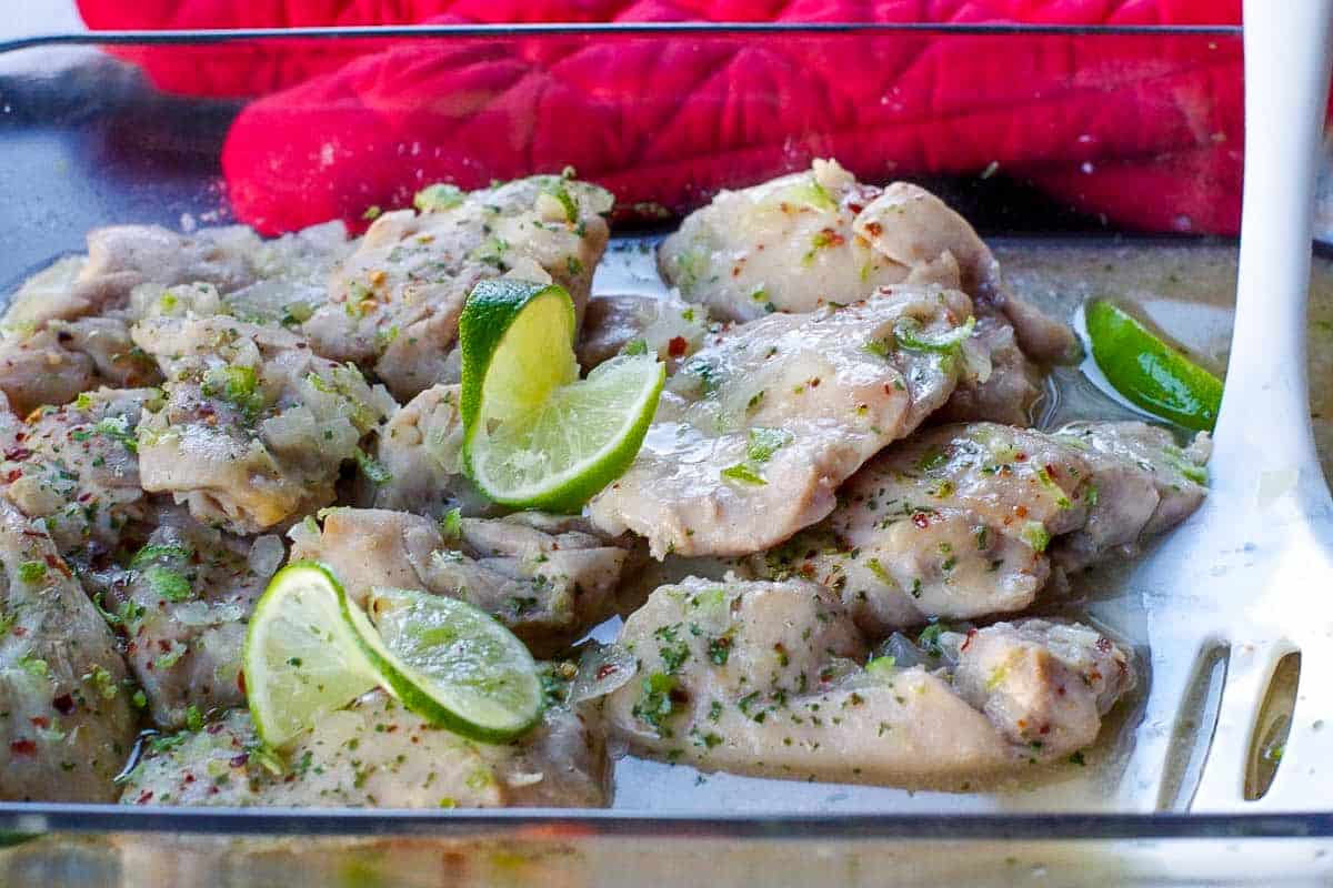 honey lime chicken in a glass casserole dish with carrots and rice in the background