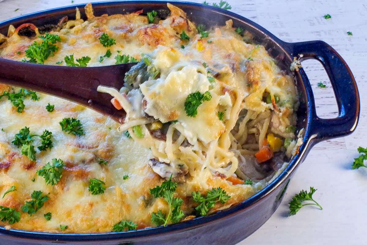turkey tetrazzini being held up on a spoon over a casserole dish