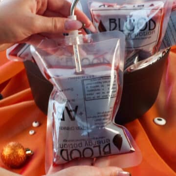 Halloween blood bag with a straw in it and more blood bags in a cauldron in the background