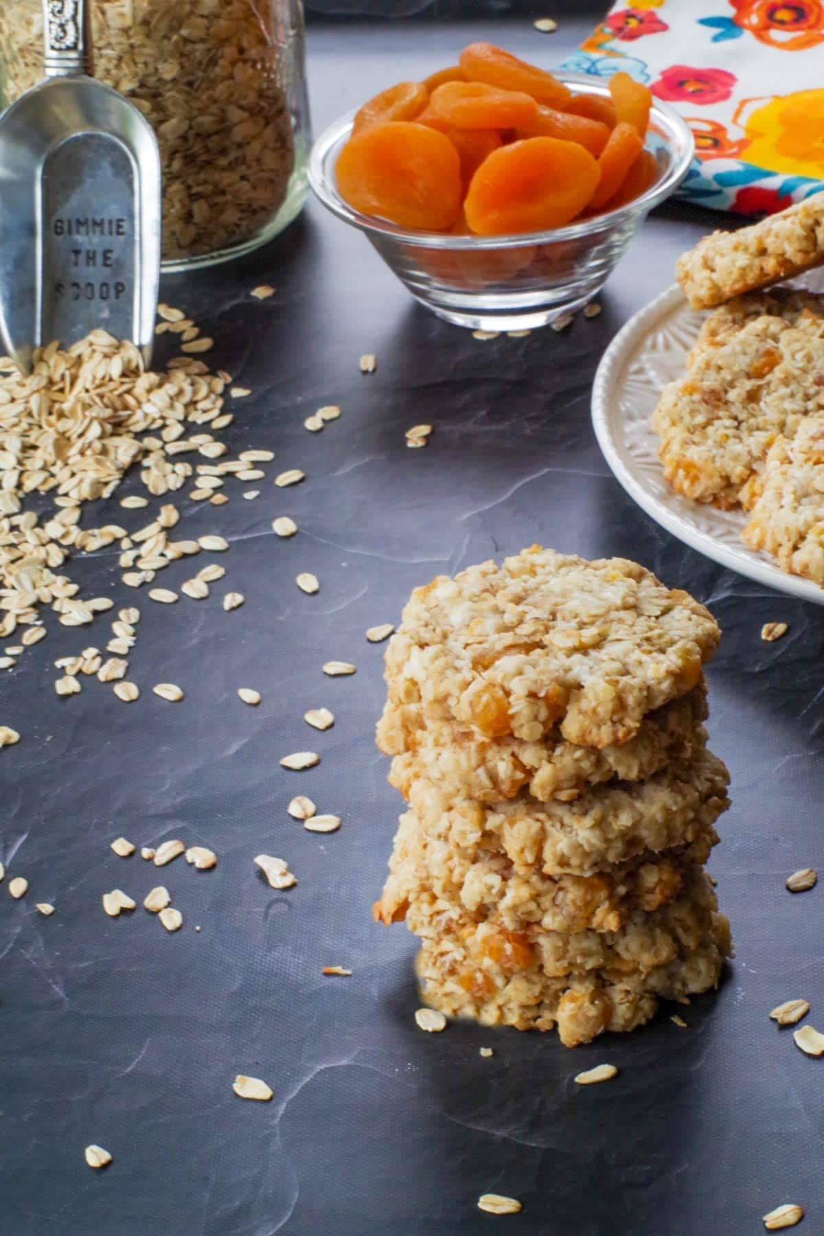 stack of Oatmeal Apricot cookies, with more cookies on a white plate in th