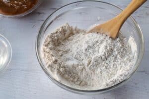 dry ingredients in medium glass bowl with wooden spoon