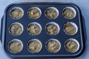 muffin liners filled with cupcake batter in 12 cup muffin tin