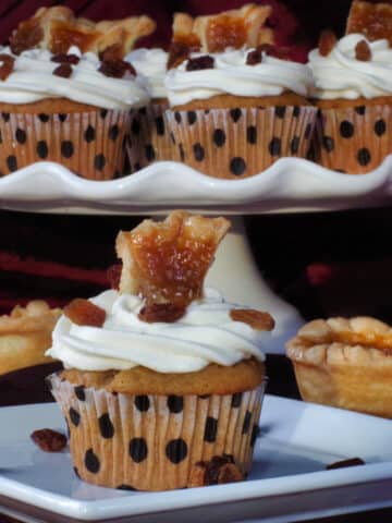 butter tart cupcake on a white plate, with platter of butter tart cupcakes in the background