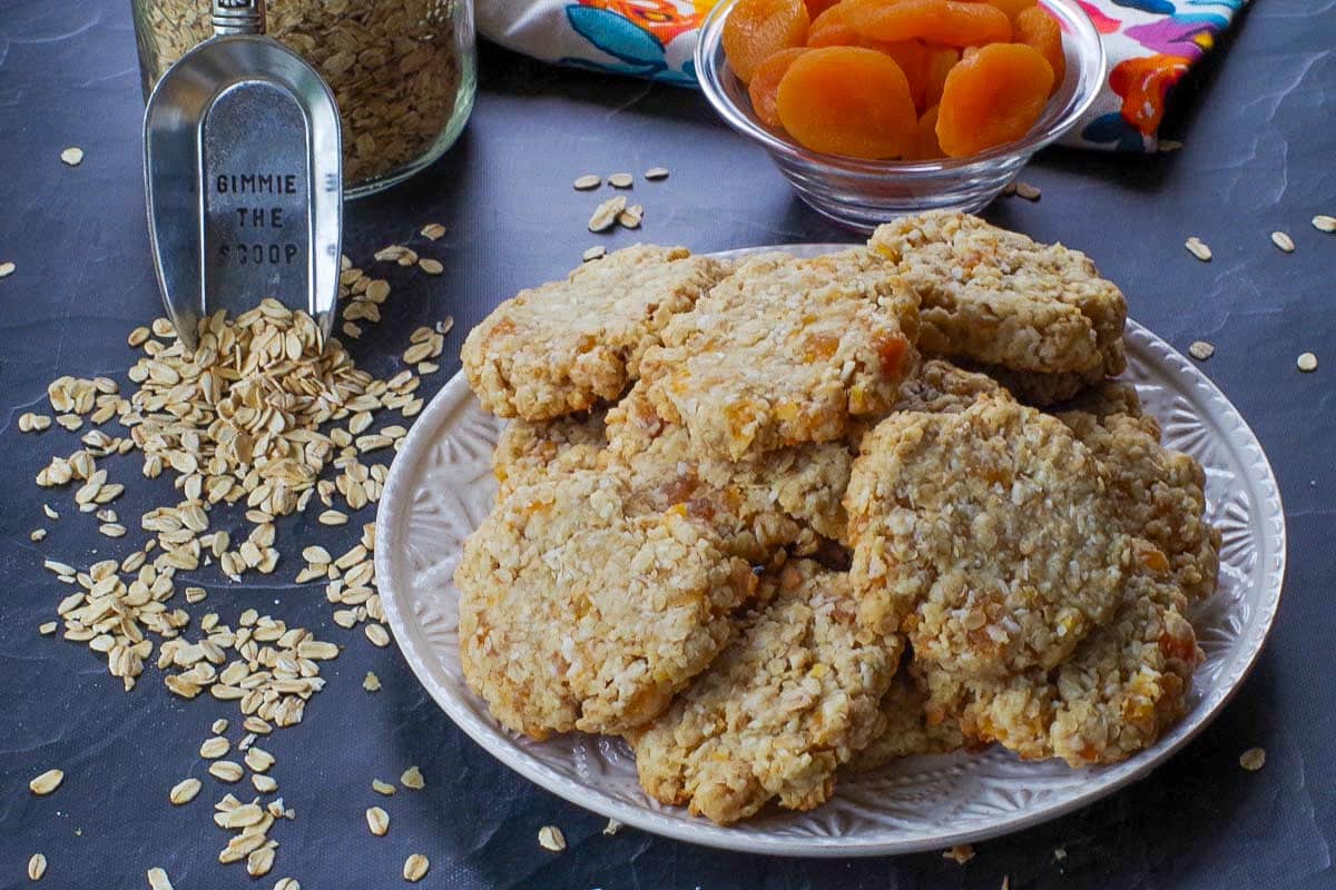 Oatmeal apricot cookies on a white plate with dried apricots in background