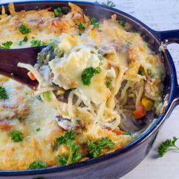 turkey tetrazzini being held up on a spoon over a casserole dish