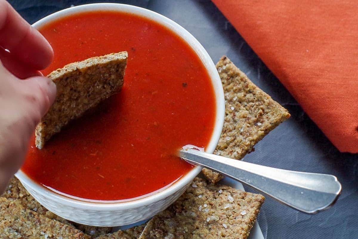 Leftover stuffing cracker being dipped into a bowl of tomato soup