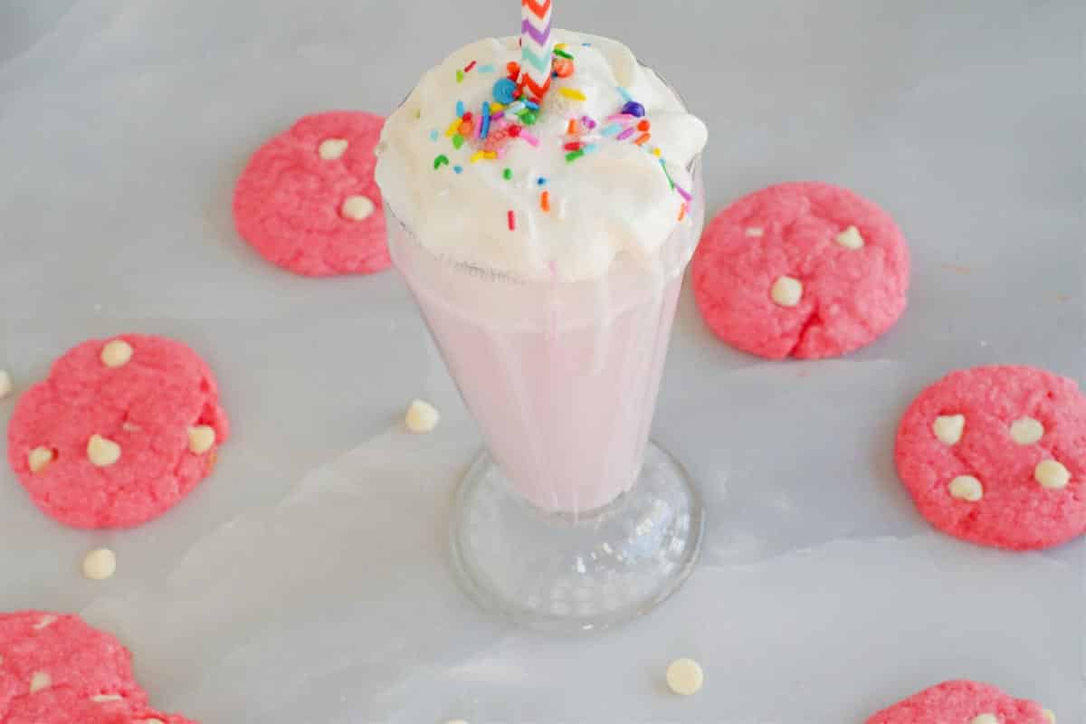 strawberry milkshake cookies in a circle around a strawberry milkshake (on grey marble background)