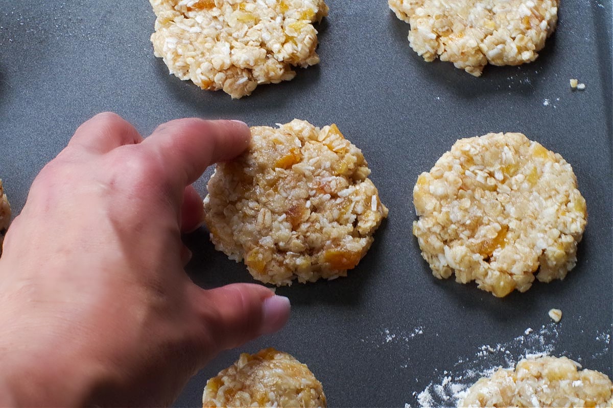oatmeal cookies on baking sheet with hand touching edges