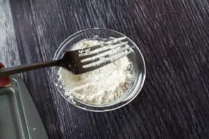 fork being dipped in flour in glass bowl
