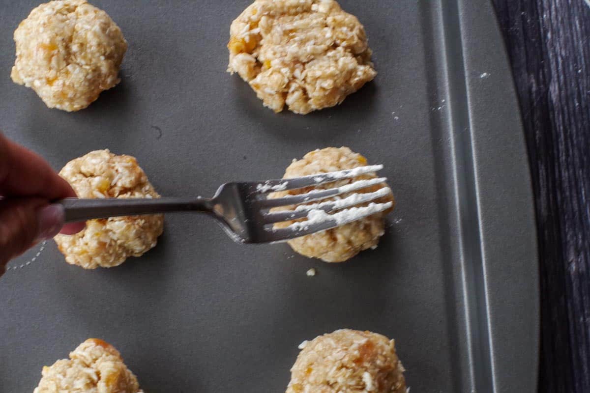 floured fork pressing down on cookie dough on baking sheet