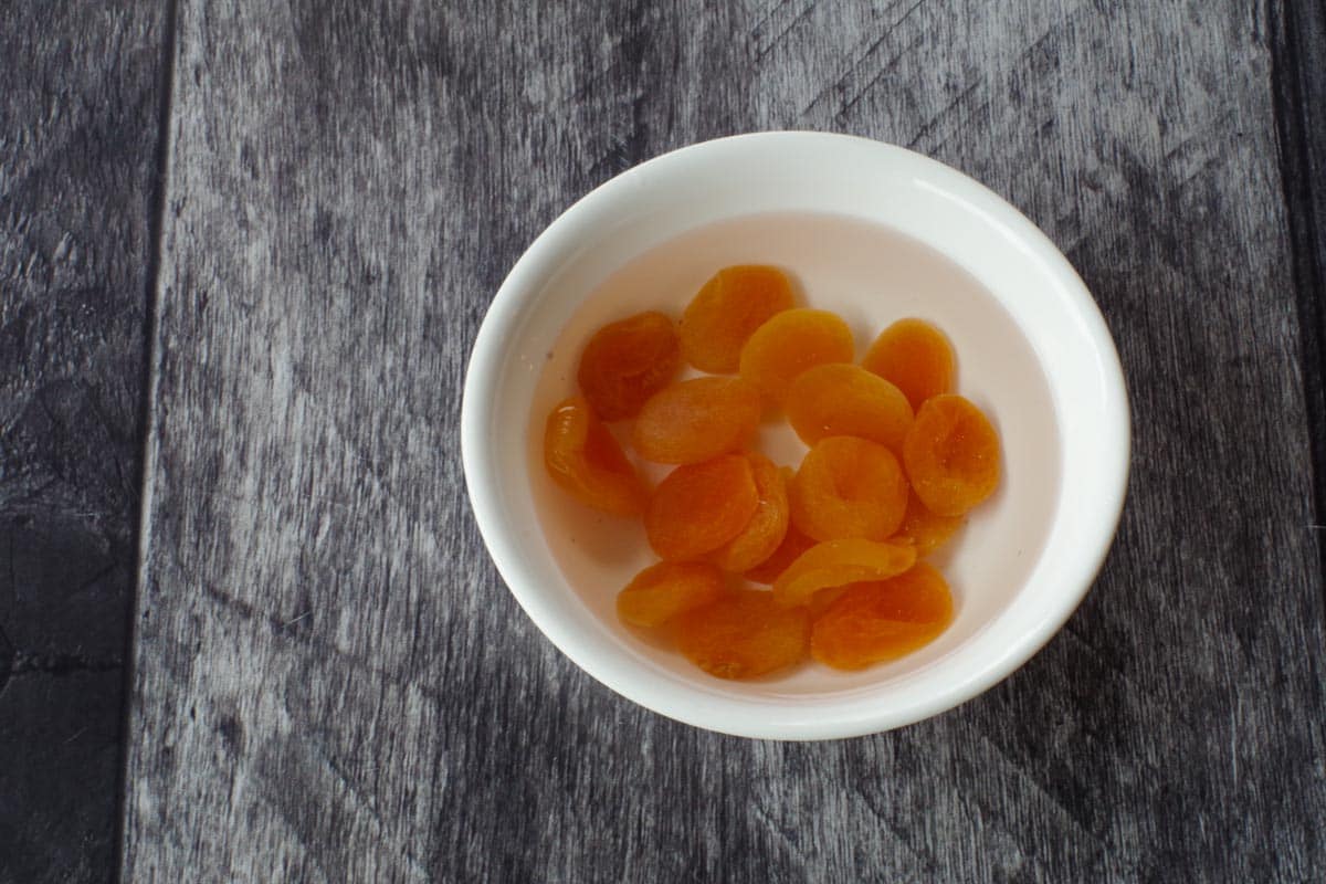 dried apricots soaking in in hot water in a white bowl