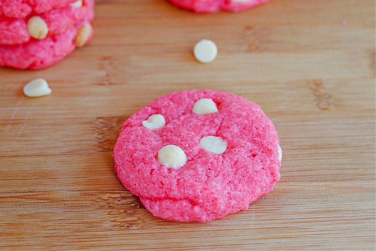 strawberry milkshake cookie on wooden cutting board with a couple of cookies in the background