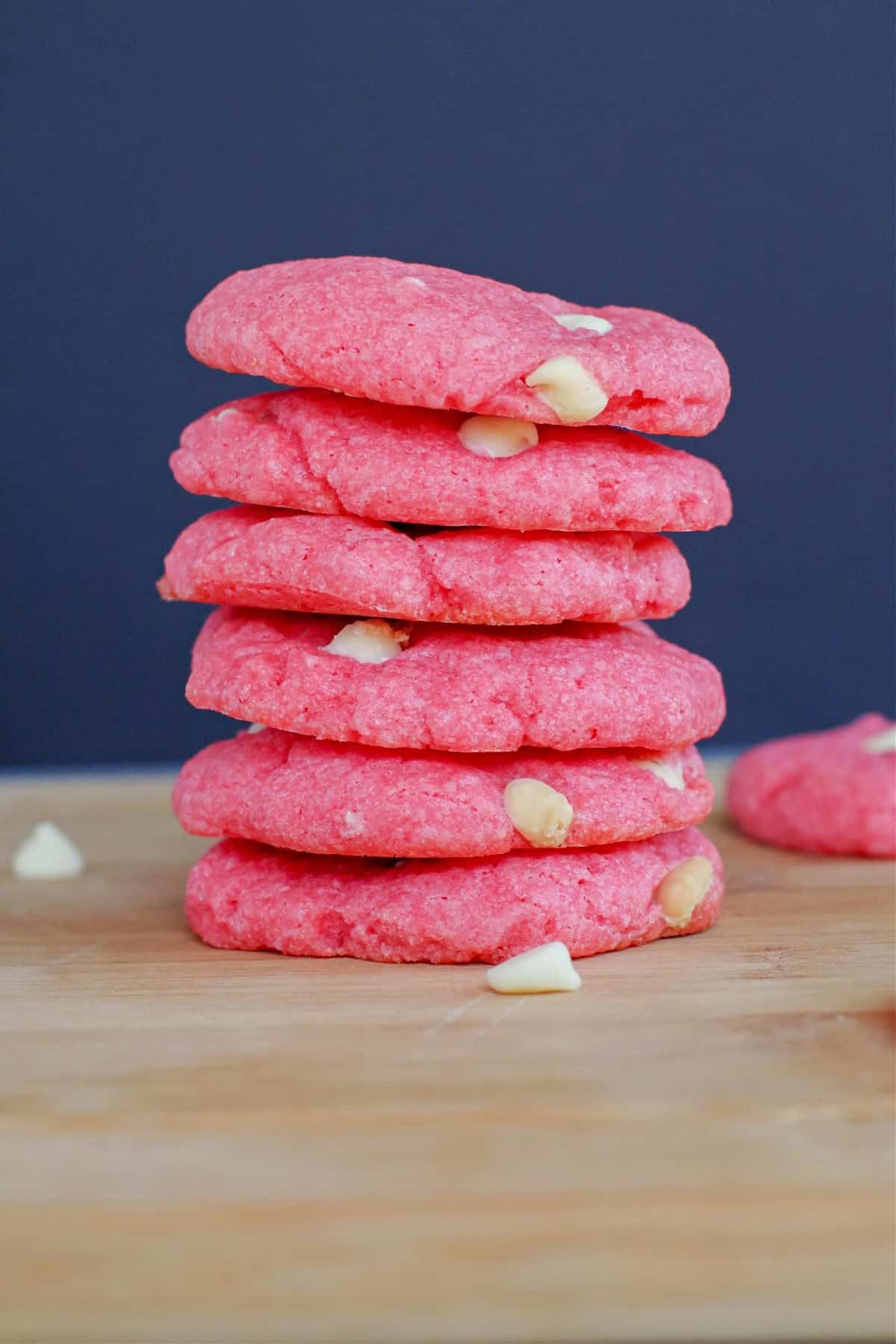 6 strawberry milkshake cookies stacked on a wood cutting board
