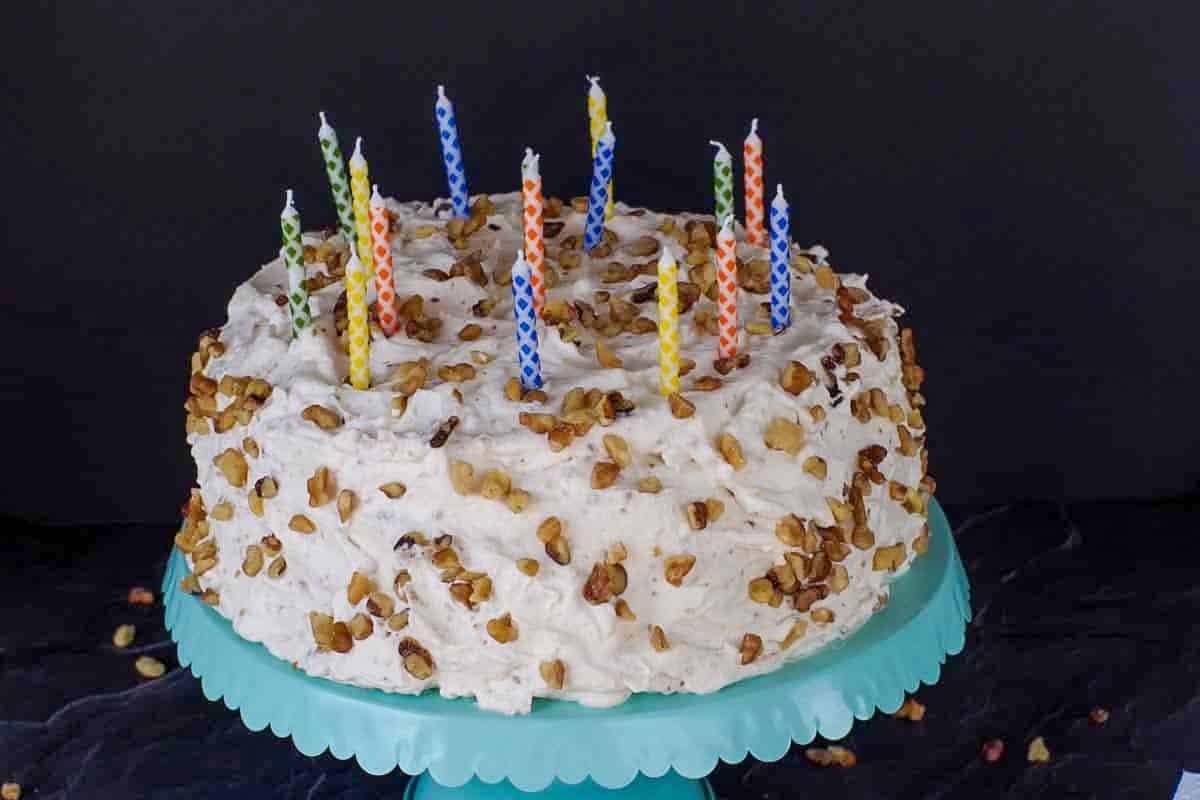 Whole Ukrainian walnut torte with candles on top, on a blue display stand