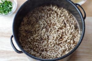 ramen noodles added to the pot with broth and beef