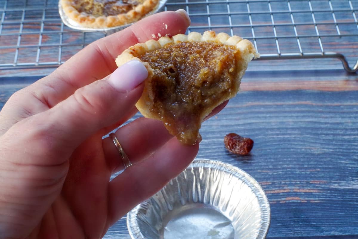 butter tart being held up with filling seeping out