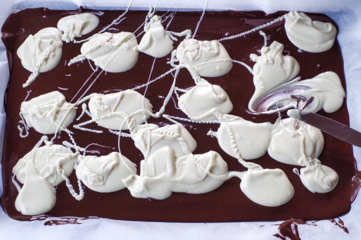 dollops of white chocolate dropped on melted semi-sweet chocolate on a sheet pan