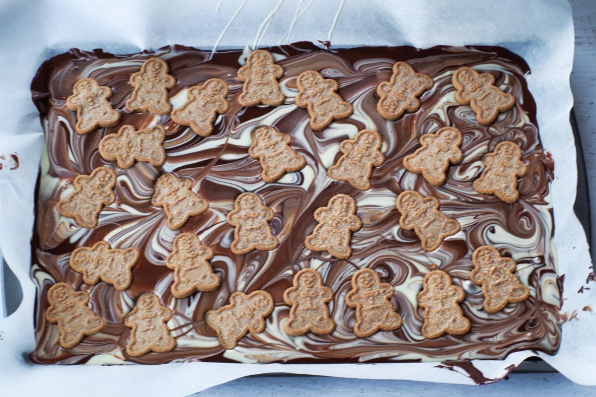 gingerbread man cookies added to marbled chocolate on sheet pan