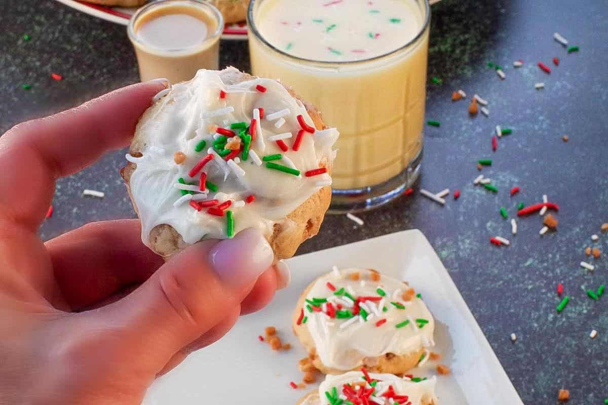 an eggnog and baileys irish cream cookie being held up over a white plate with more cookies