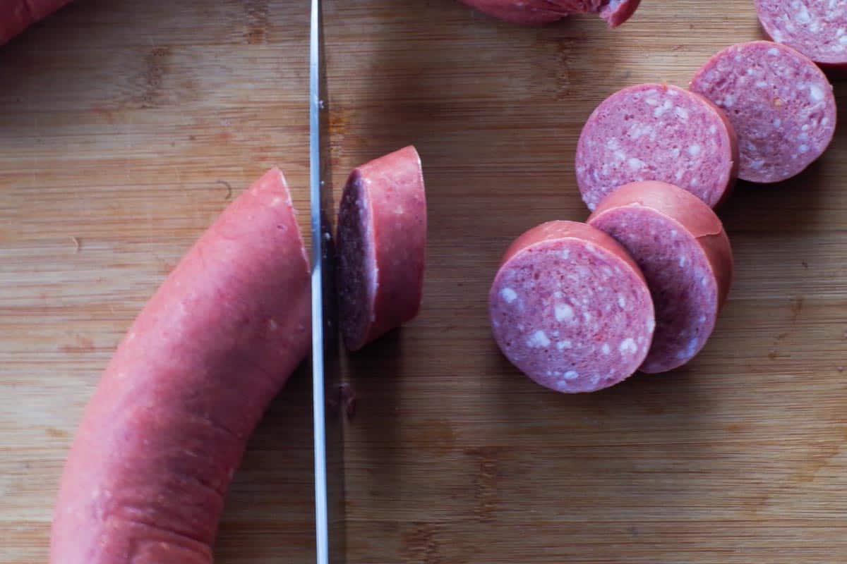 kielbasa on cutting board, being sliced into ½ inch rounds