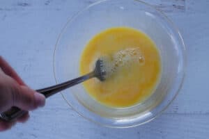 eggs being beaten with fork in glass bowl