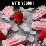 strawberry yogurt popsicles on a black counter surface with ice and fresh strawberries