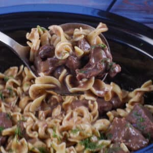 light beef stroganoff being ladled out of slow cooker