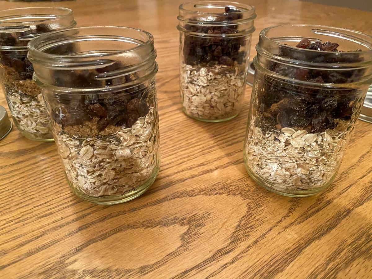 4 jars with oats, raisins, brown sugar and chia on a table