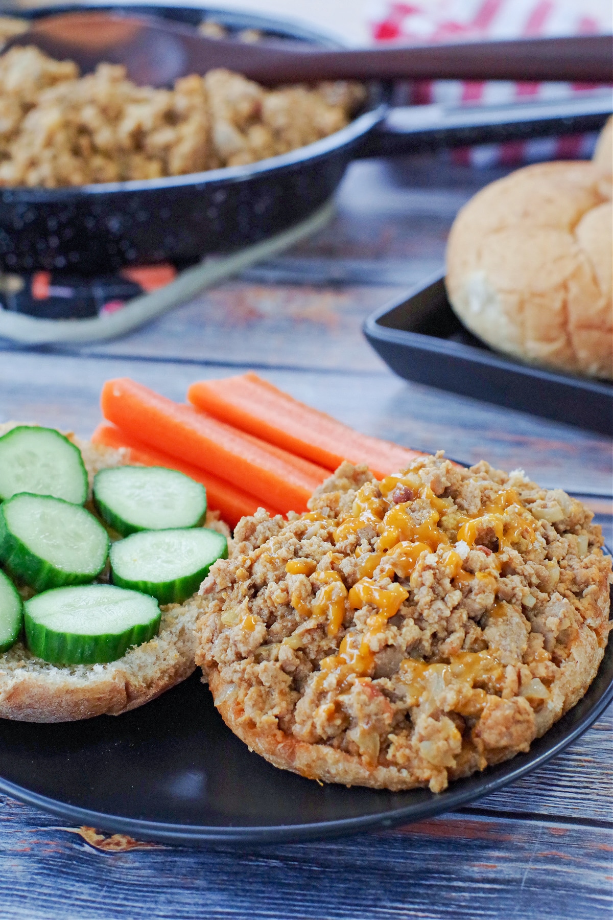 weight watchers turkey sloppy joes on a black plate with veggies and a skillet of more in the background