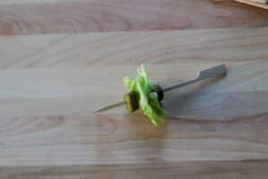 a skewer with pickles and lettuce on a wooden cutting board