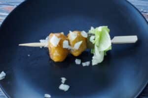 chopped onion added to the skewer, on a black plate