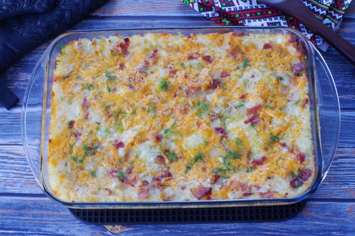 baked lazy pierogi casserole, garnished with dill in glass 9x13 pan
