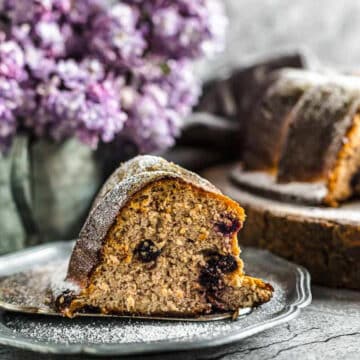 blueberry bundt cake on a plate with purple flowers in the background