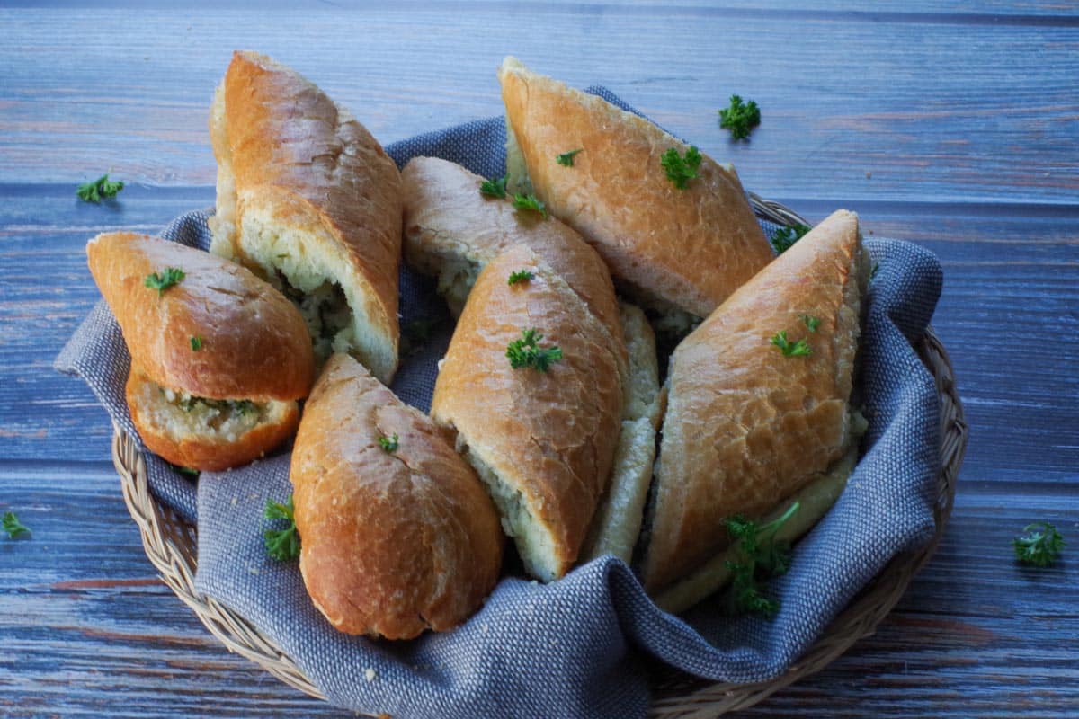 sliced baguette garlic bread in a small basket with a grey liiner
